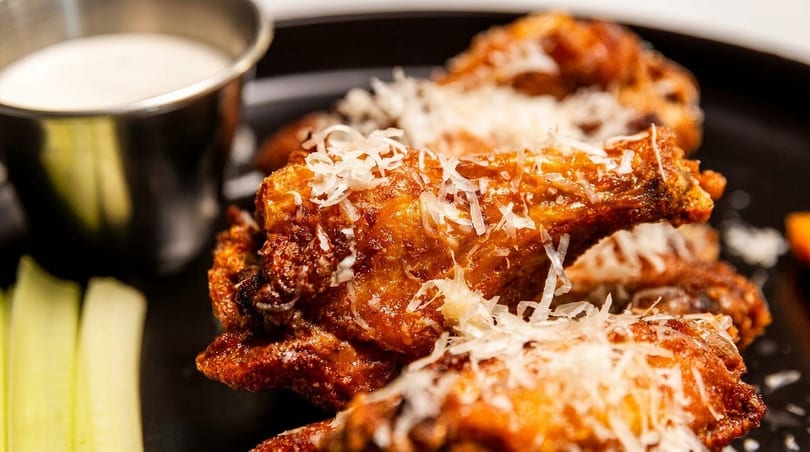Crispy chicken wings topped with grated cheese, served with celery sticks and a side of ranch.